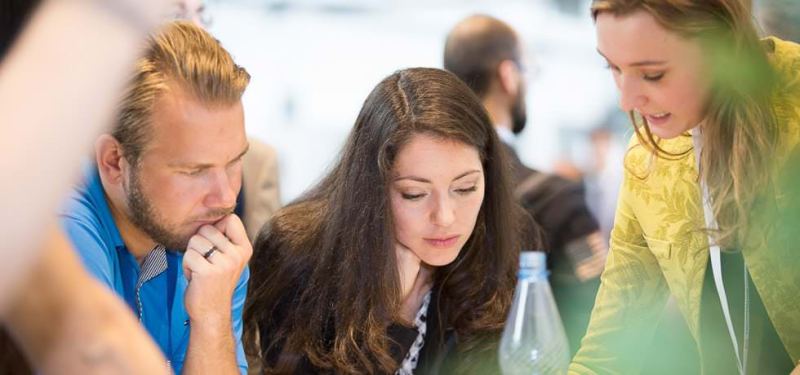Drei Messebesucher schauen gemeinsam in Unterlagen
